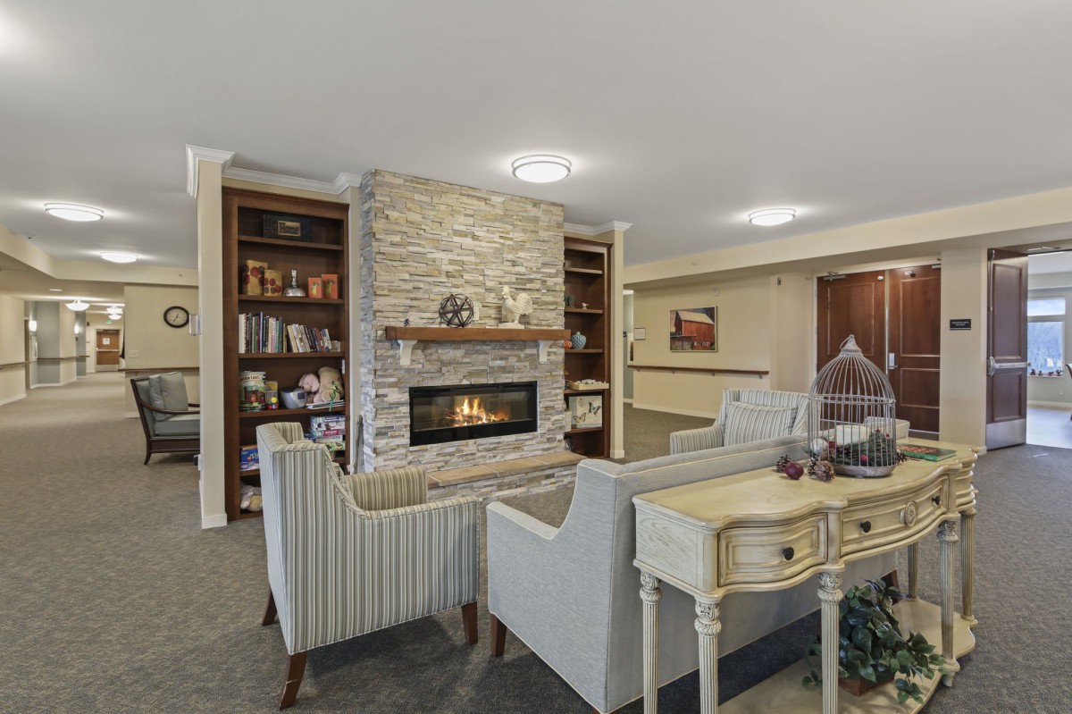 A cozy living room featuring a stone fireplace, comfortable seating, and built-in bookshelves.