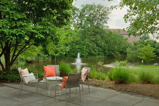 A serene outdoor seating area by a tranquil fountain, surrounded by lush greenery.