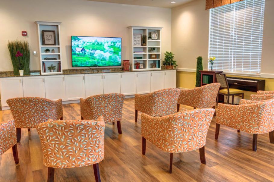 A cozy living room setup with patterned chairs facing a large television, flanked by shelves filled with decor.