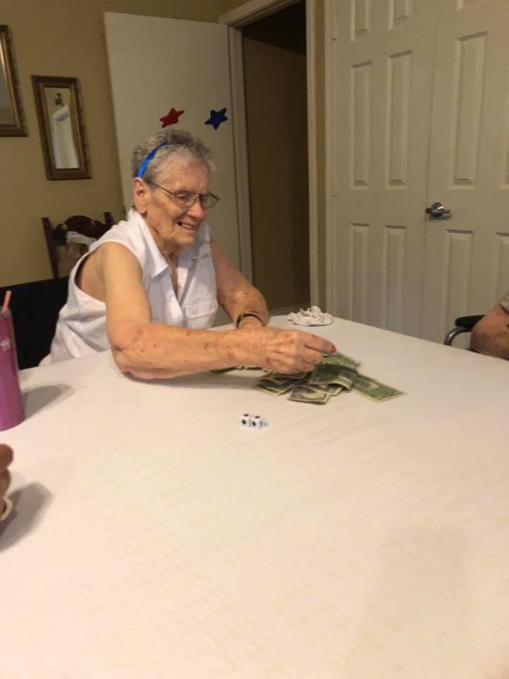 An elderly woman playing cards at a table indoors.