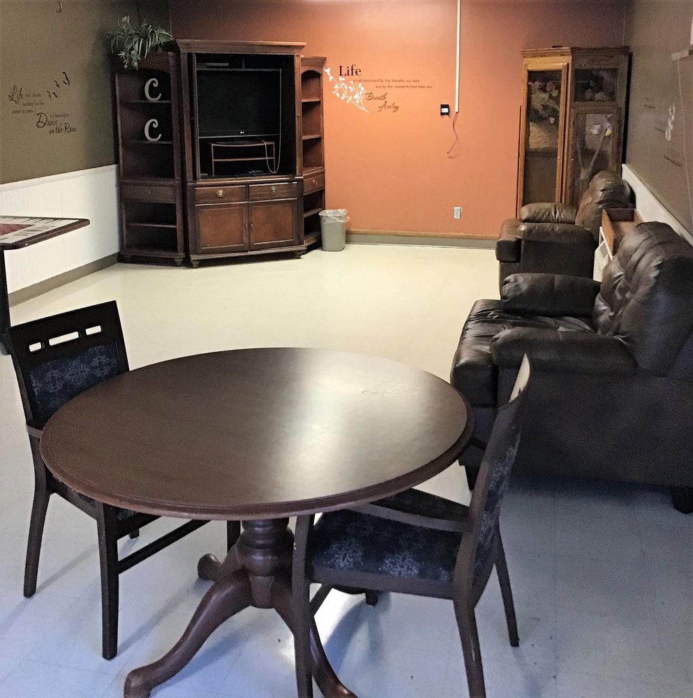 A cozy living room with a small dining table and chairs, a sofa, and a television.