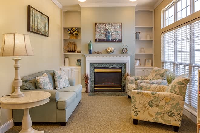 A cozy living room with a fireplace, sofas, and decorative shelves.