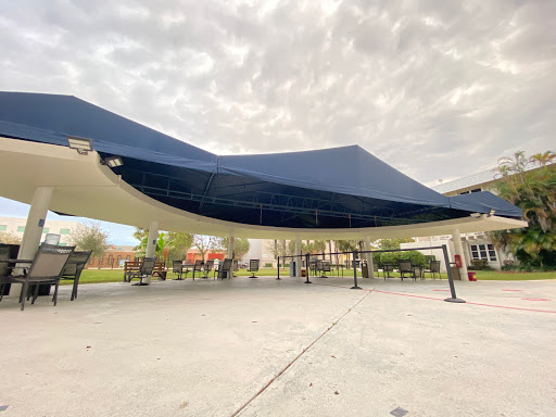 A blue canopy providing shade in an outdoor space, set against a cloudy sky.