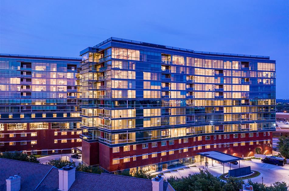 A modern apartment complex illuminated at night, showcasing its architectural design.