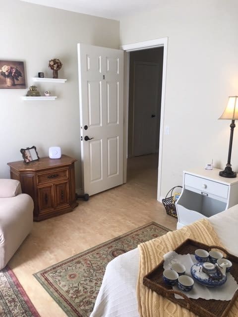 A cozy living room with a sofa, lamp, and open door leading to another room.
