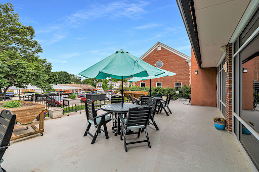A cozy outdoor patio area featuring tables and chairs shaded by a large umbrella, perfect for relaxation.