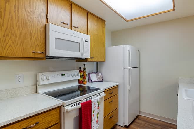 A modern kitchen with wooden cabinets, featuring a stove, microwave, and refrigerator.