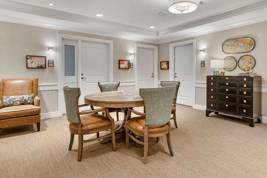 A cozy dining area with a round wooden table surrounded by four chairs, elegant lighting, and tasteful decor.