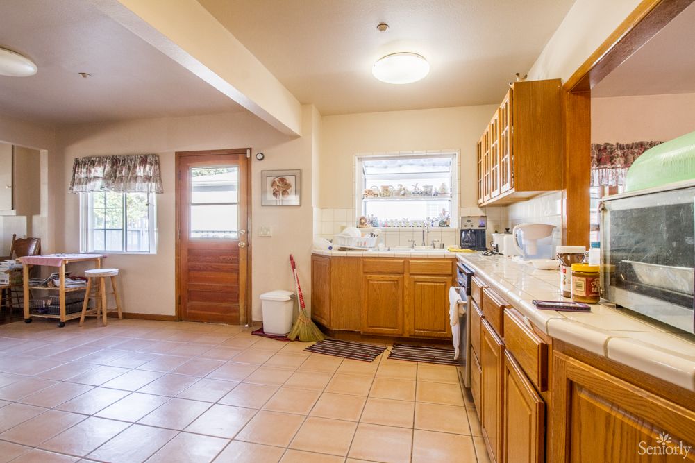 A spacious kitchen with wooden cabinets and tiled flooring.