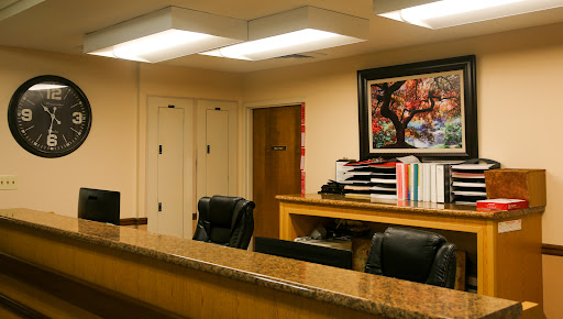 A well-organized office reception area featuring a desk, chairs, and decorative artwork.