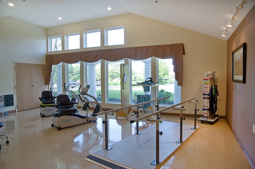 A well-lit rehabilitation center featuring various exercise equipment for physical therapy.