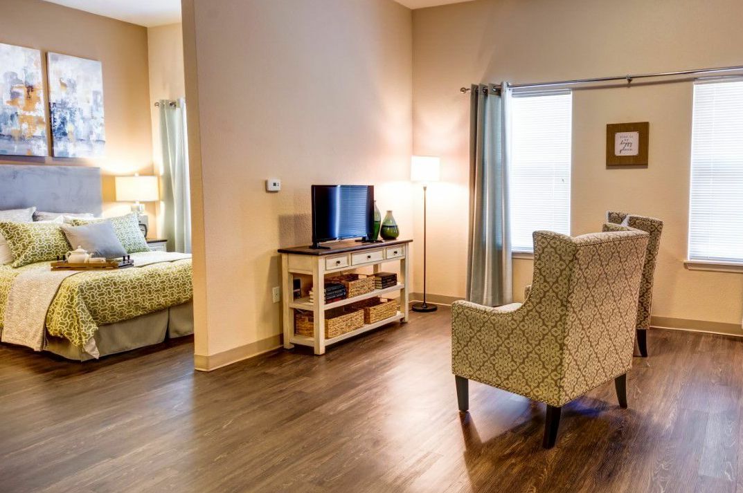 A cozy living space with a TV, lamp, and armchair adjacent to a bedroom.