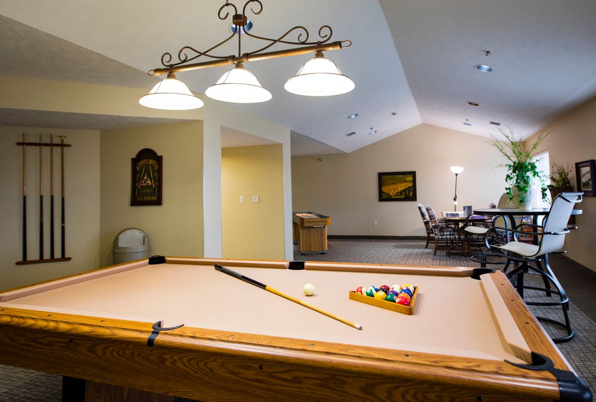 A cozy game room featuring a pool table with cue sticks and balls ready for play.