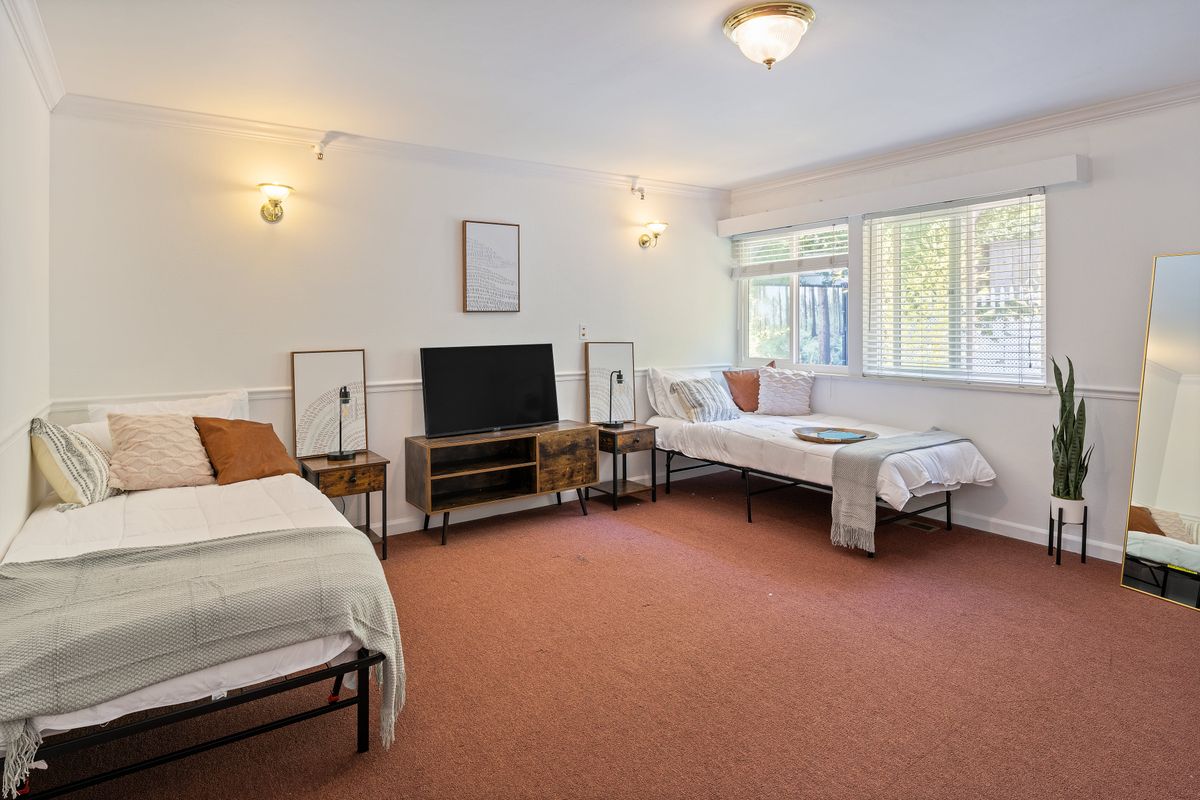 A spacious bedroom with two beds, a television, and ample natural light.