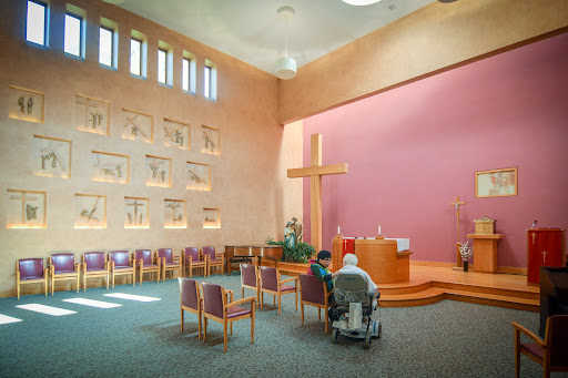 An interior view of a church featuring a prominent cross and seating arrangements for worshippers.