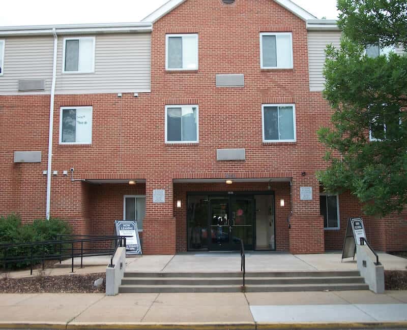 Front view of a brick residential building with stairs leading to the entrance.