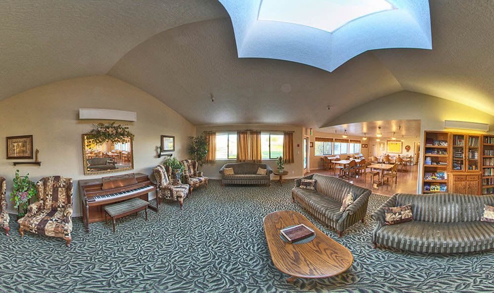 Spacious living room with a skylight and elegant furnishings, including sofas, a coffee table, and a piano.