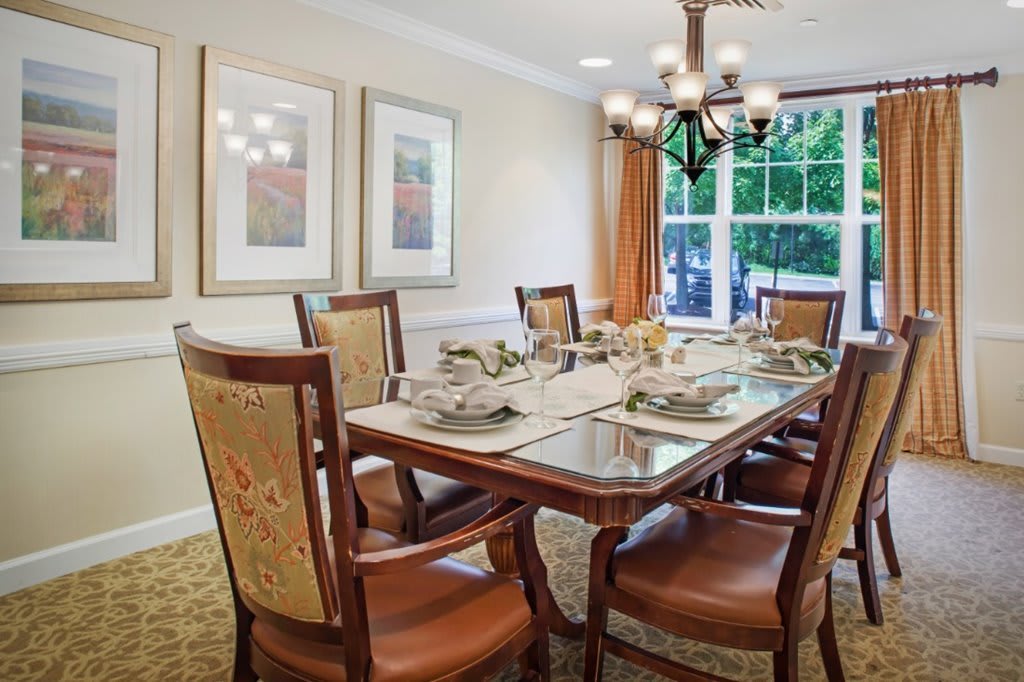 A well-decorated dining room with a set dining table and elegant chairs under a chandelier.