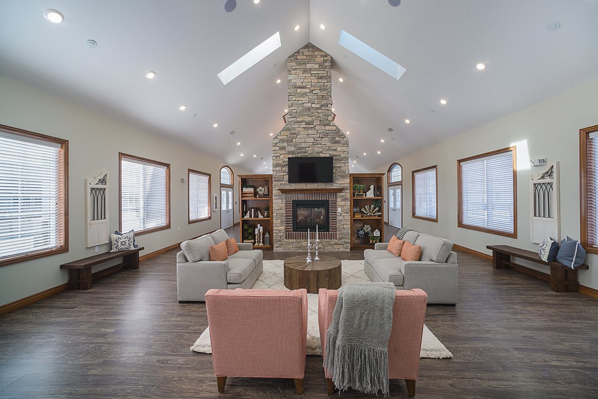 A modern living room with a central stone fireplace, skylights, and comfortable seating.