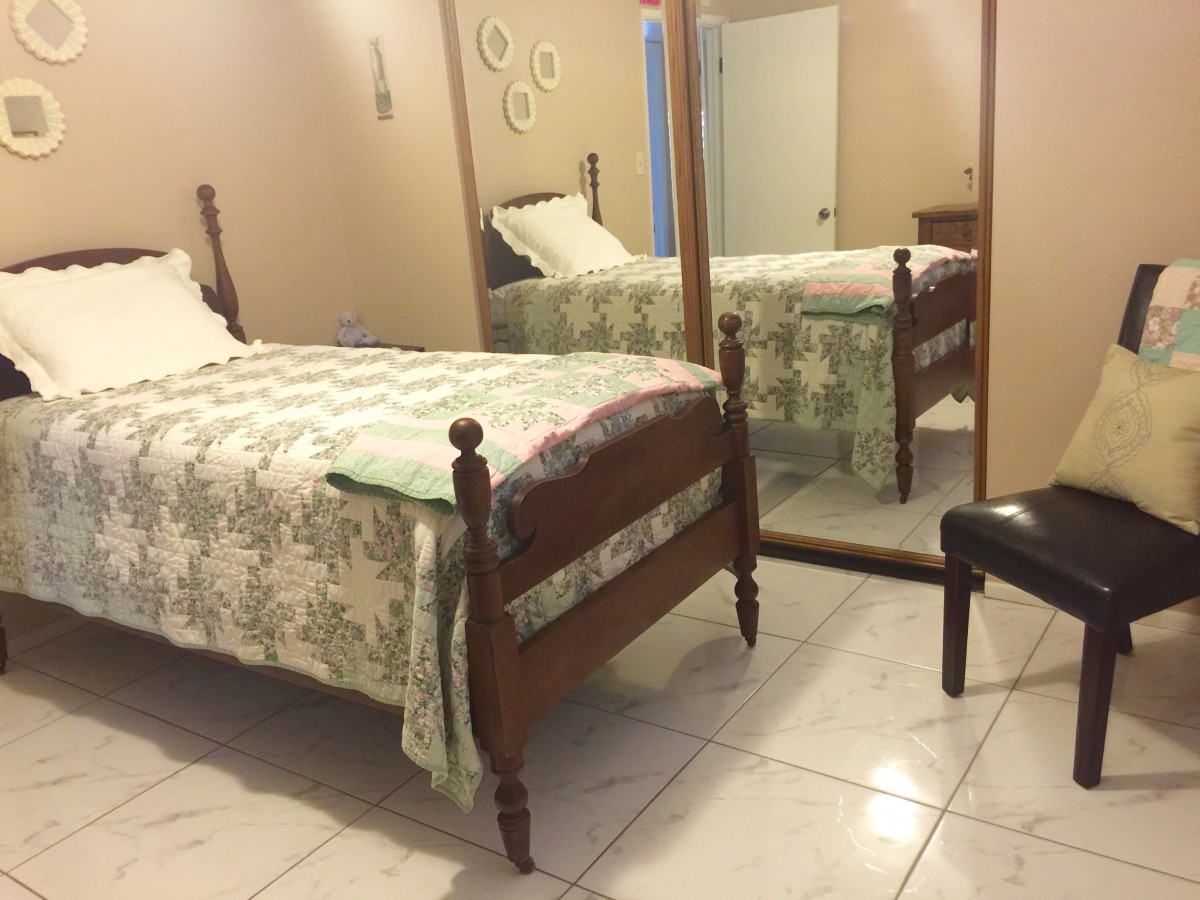 A cozy bedroom with a single bed and large mirror.