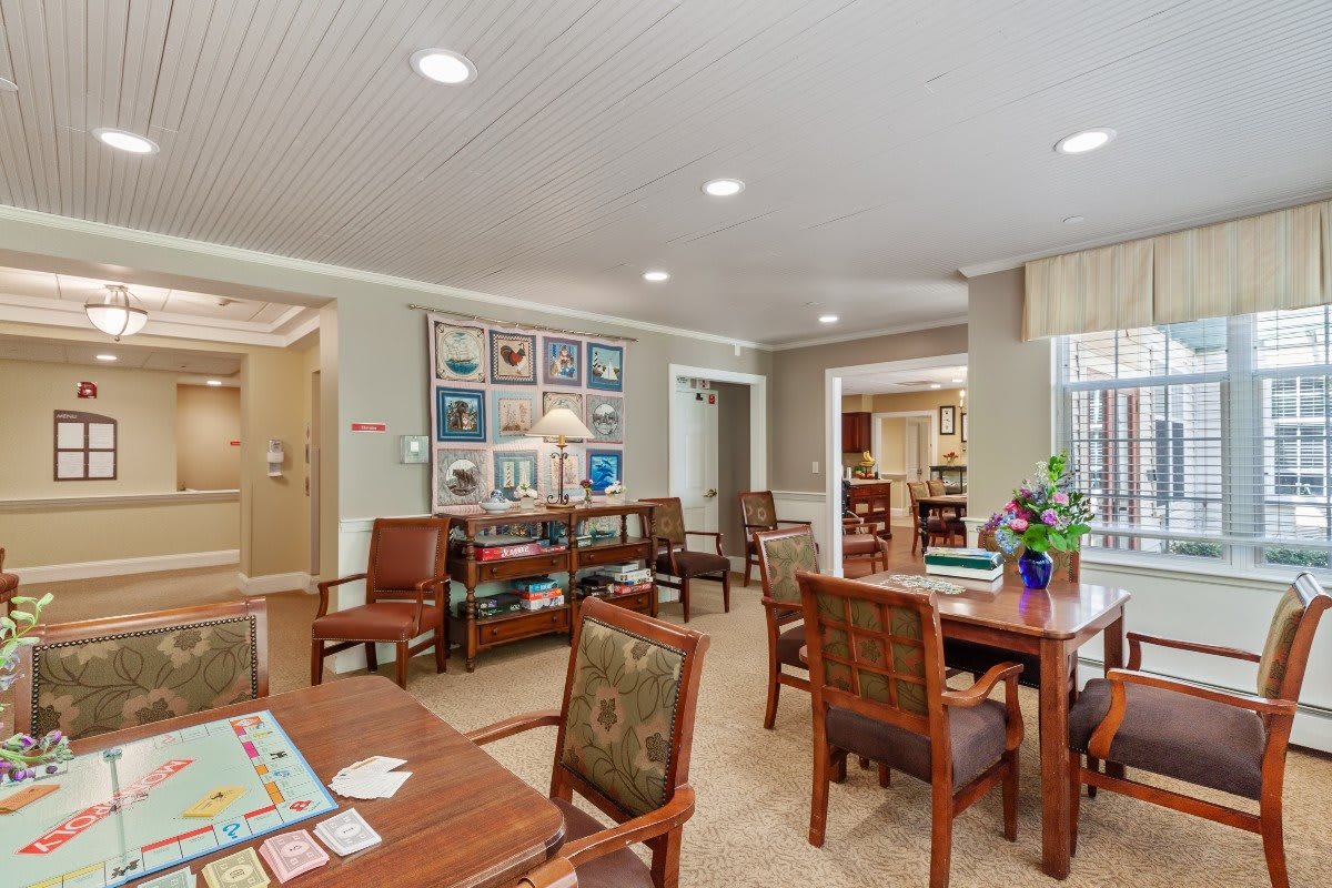 A cozy community living area featuring tables and chairs arranged for social activities.