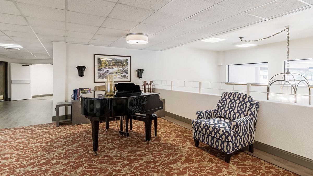 A cozy interior space featuring a grand piano, patterned armchair, and elegant decor.