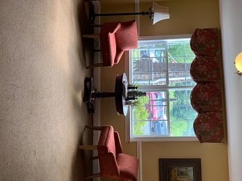 A cozy sitting area with two chairs, a small table, and a lamp next to a window.
