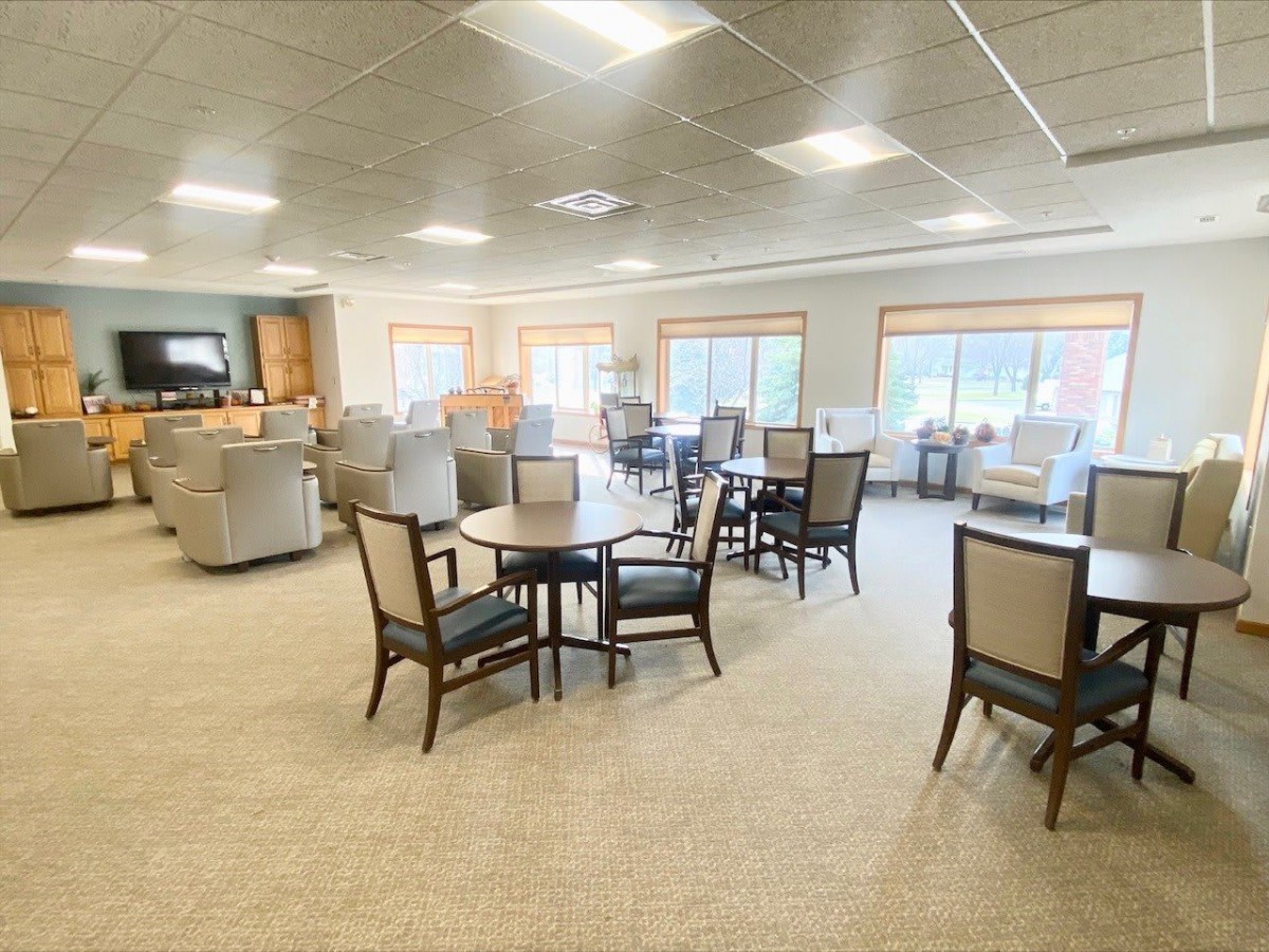 A spacious dining area with multiple tables and chairs, well-lit by natural and artificial lighting.