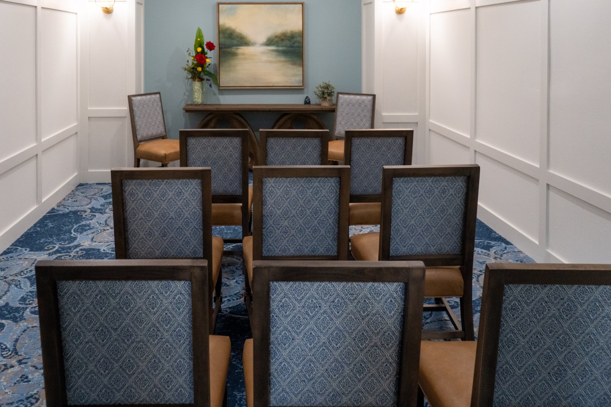 An empty conference room set up with chairs facing a small table and a landscape painting on the wall.