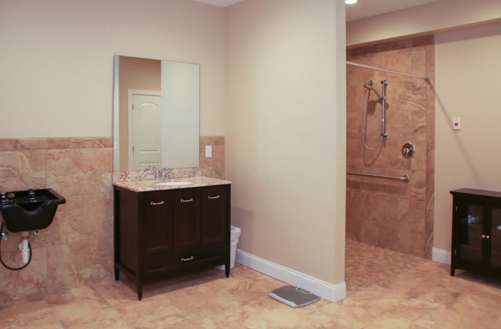 A modern bathroom featuring a dark vanity with a mirror and a spacious shower area.