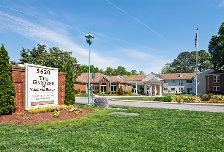 A building with a sign in front, surrounded by green grass and clear blue sky.
