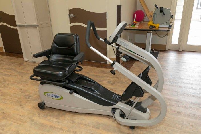 A seated exercise machine designed for cardio workouts, featuring pedals and handlebars.