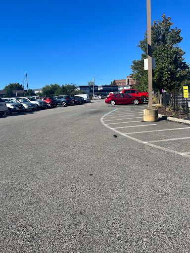 A view of a spacious parking lot filled with cars under a clear blue sky.