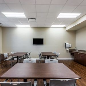 A conference room with tables, chairs, and a wall-mounted television.