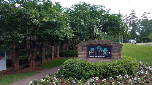 The entrance to Hilltop, surrounded by lush greenery and blooming flowers.