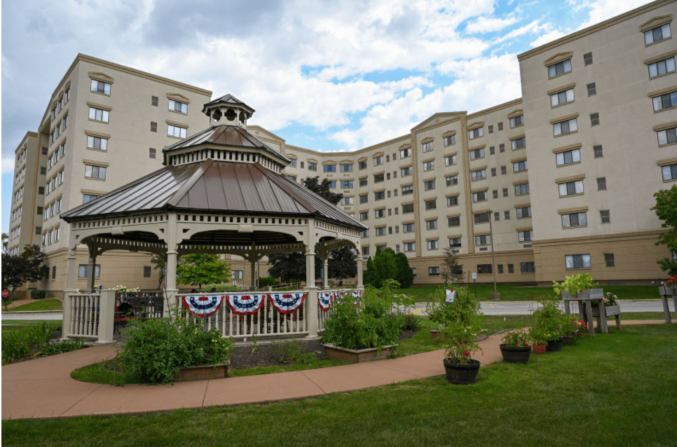 A decorated gazebo in front of a large residential building surrounded by greenery.