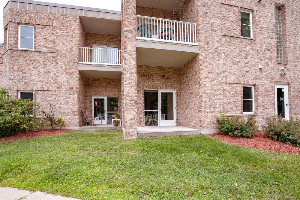 A brick apartment building with balconies and a well-maintained lawn in front.