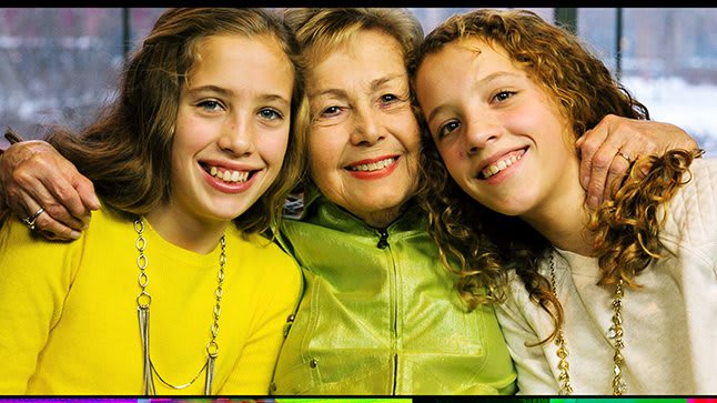 A cheerful family portrait with a grandmother and two children smiling together.