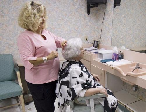 A hairdresser is styling the hair of an elderly woman in a salon.