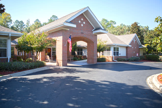 A brick building with a covered entrance and an American flag displayed in front.