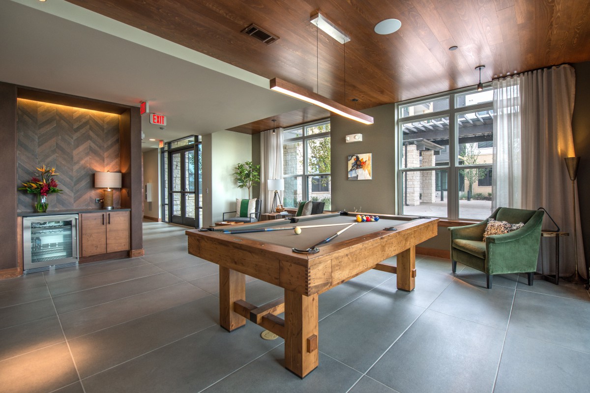 A modern game room featuring a wooden pool table and stylish seating.