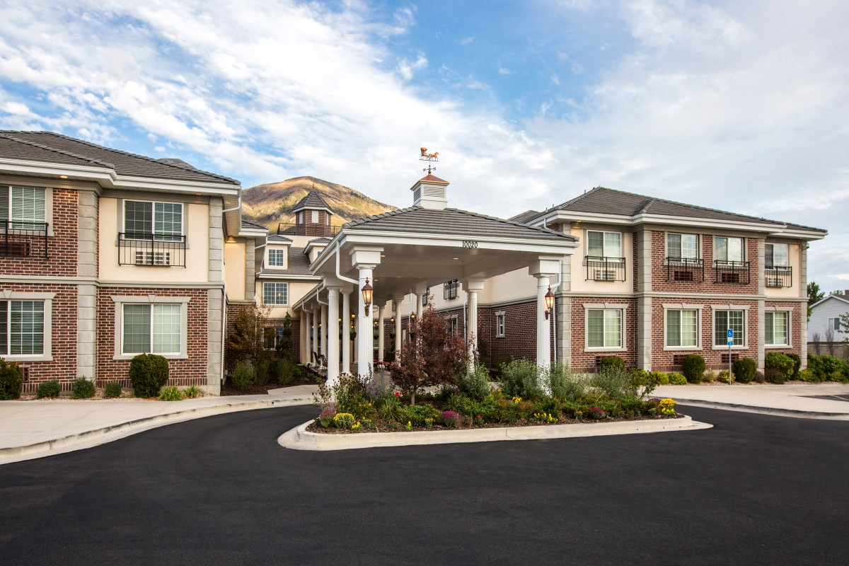 A modern residential building with a landscaped entrance and covered driveway.