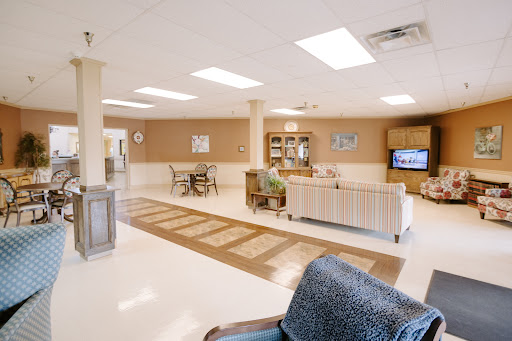 A spacious and well-lit lounge area featuring comfortable seating, a television, and dining arrangements.