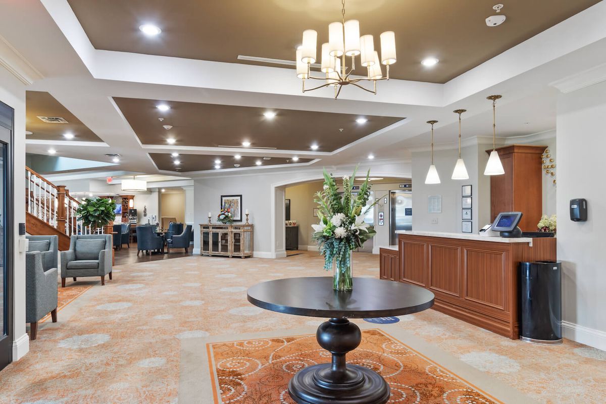 A spacious and elegantly designed lobby with a reception desk and central table adorned with flowers.