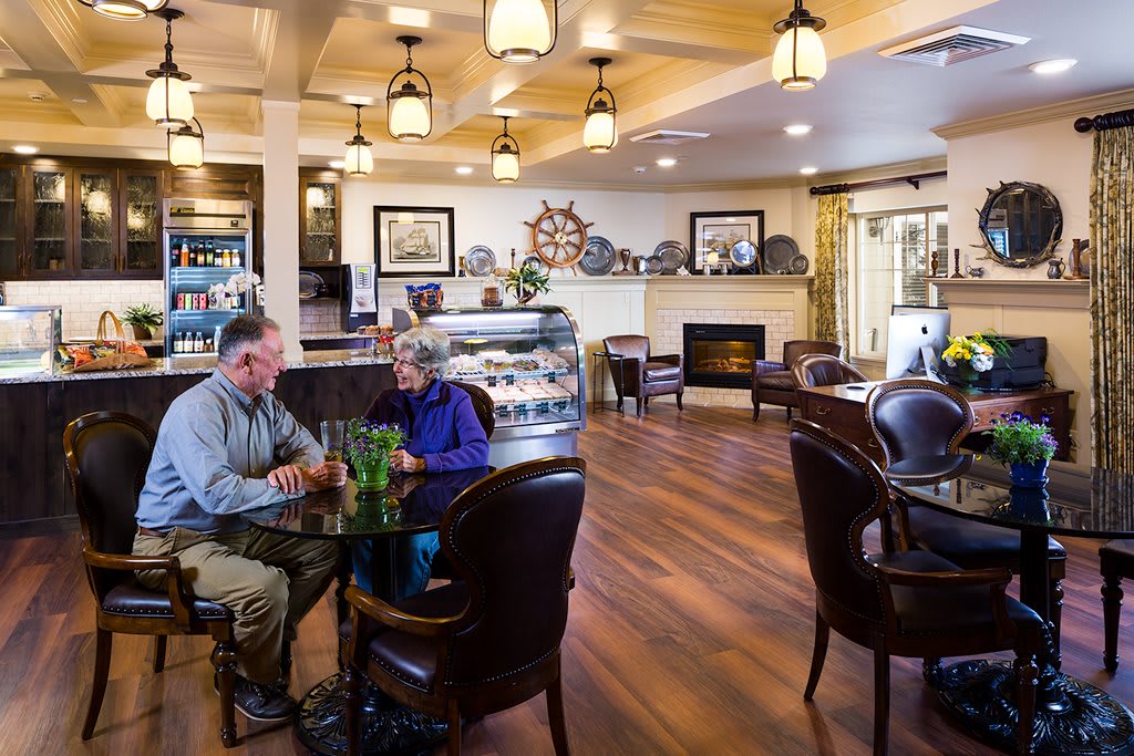 A cozy cafe with comfortable seating and warm lighting, where people enjoy a relaxing conversation.
