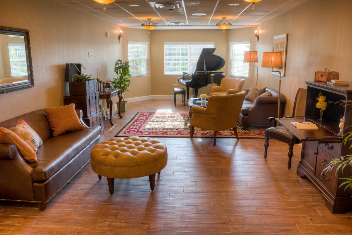 A cozy living room with a piano, featuring comfortable seating and warm lighting.