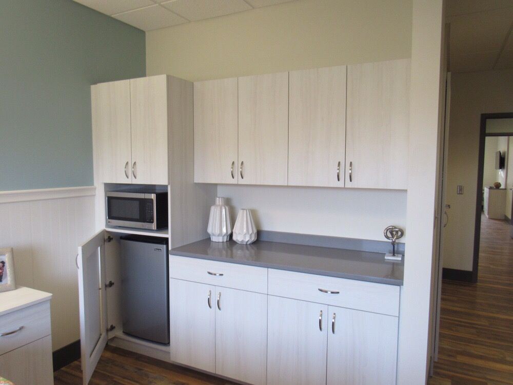 Modern kitchen area with white cabinets, a microwave, and decorative vases on the countertop.
