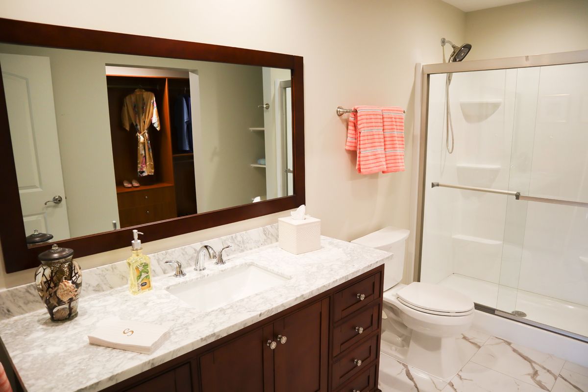 A modern bathroom with a large mirror, sink, toilet, and shower area.