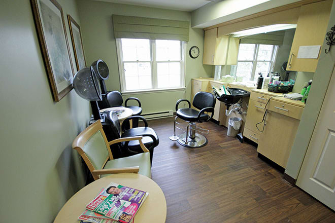 A cozy hair salon with styling chairs, a hair dryer, and a waiting area with magazines.