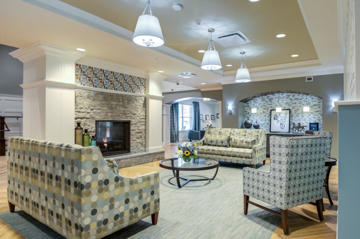 A cozy living room with elegant furniture, a stone fireplace, and modern lighting.